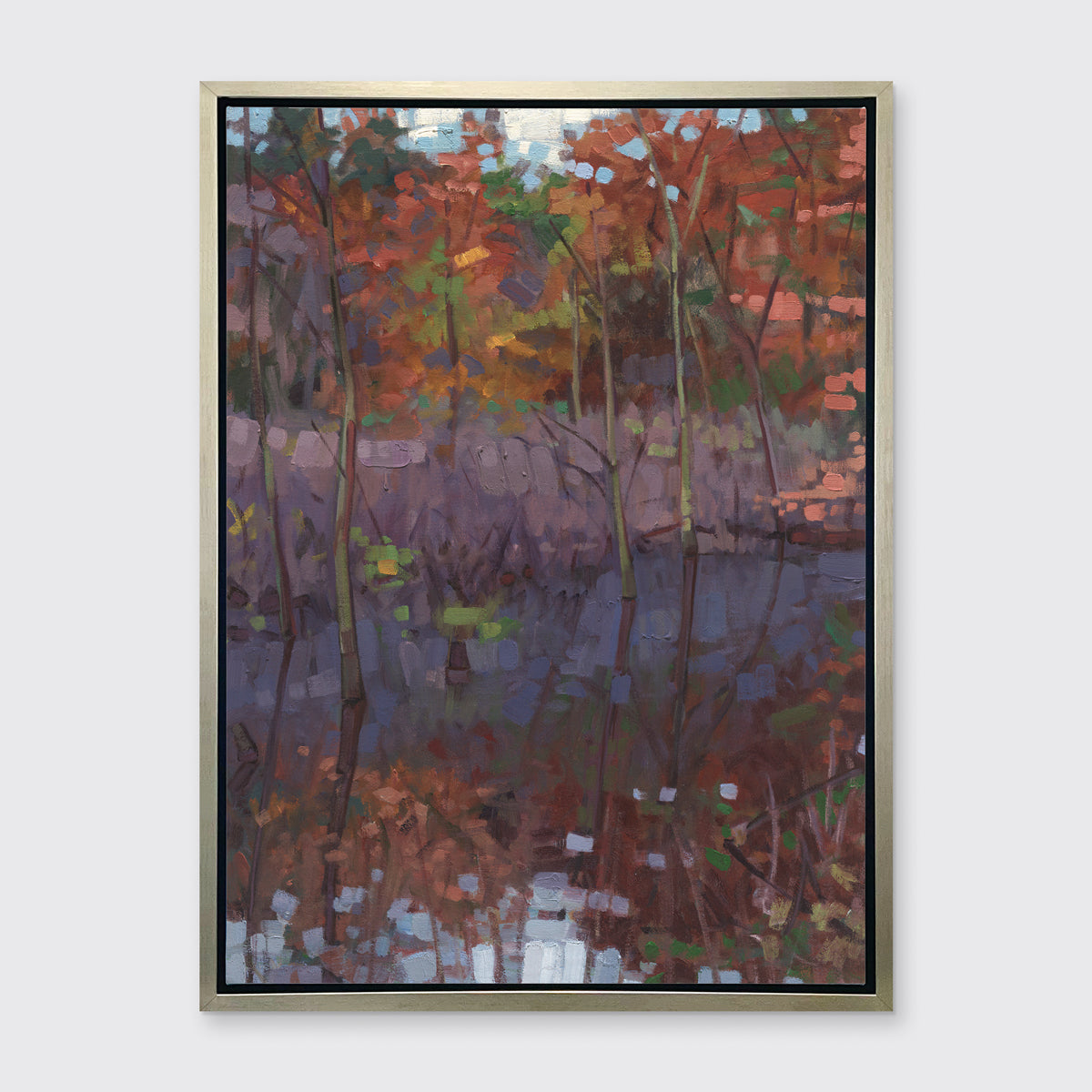 A muted multicolored abstract landscape print in a silver floater frame hangs on a white wall.