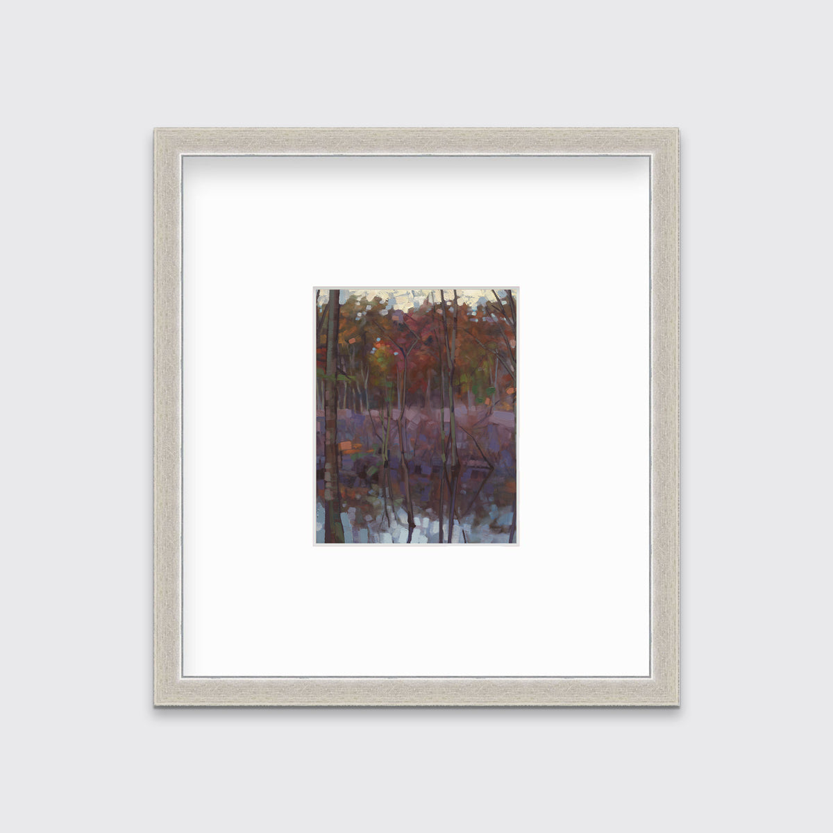 A muted multicolored abstract landscape print in a silver frame with a mat hangs on a white wall.