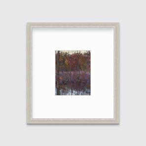 A muted multicolored abstract landscape print in a silver frame with a mat hangs on a white wall.
