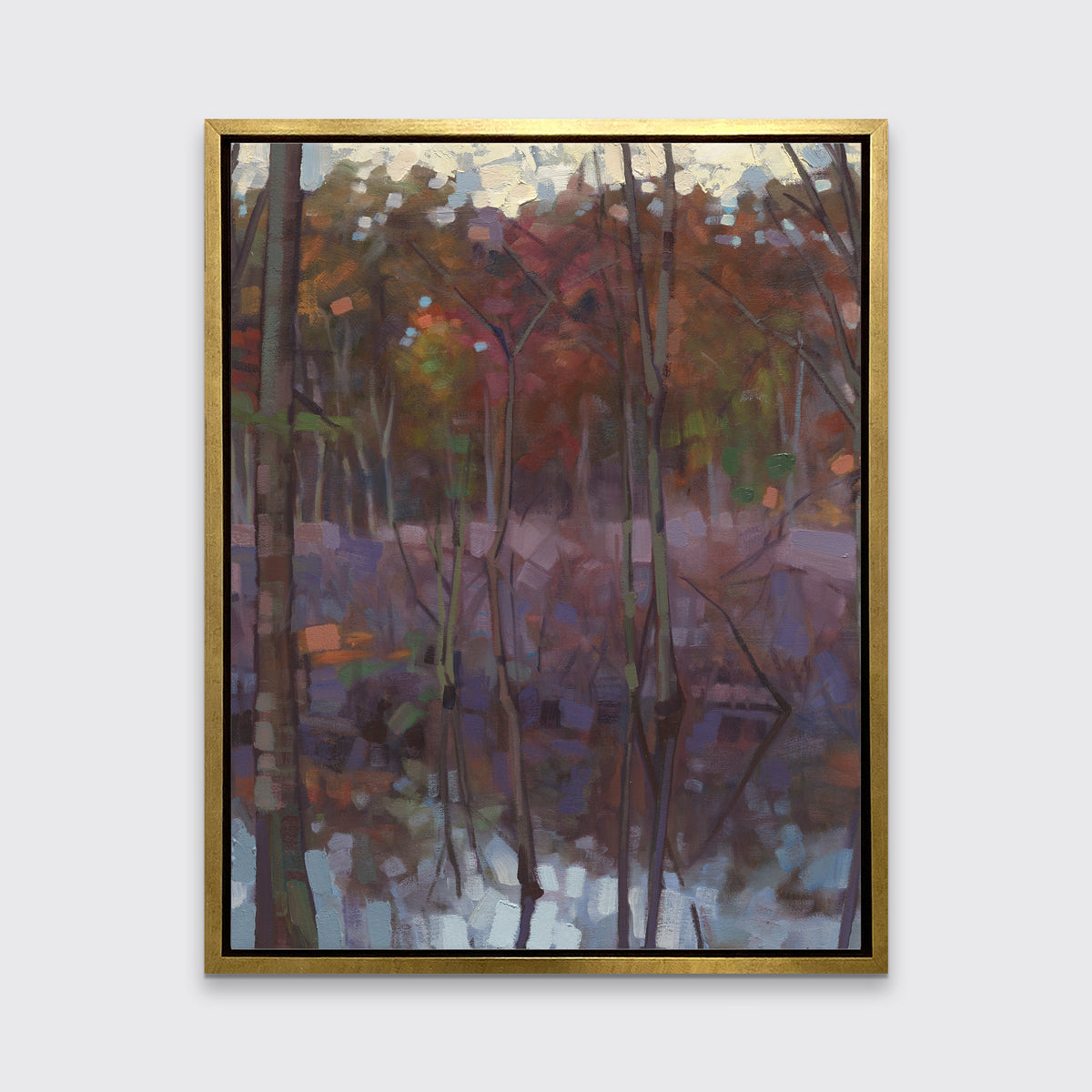 A muted multicolored abstract landscape print in a gold floater frame hangs on a white wall.