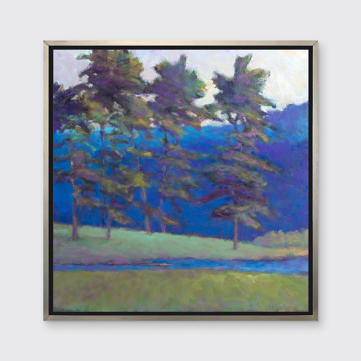 A blue and green tree landscape print in a silver floater frame hangs on a white wall.