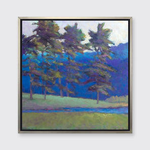 A blue and green tree landscape print in a silver floater frame hangs on a white wall.