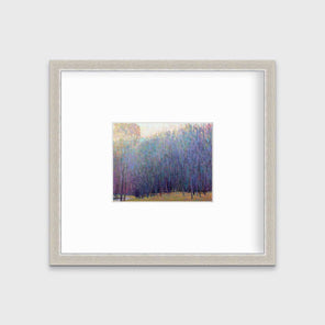 A blue and purple abstract tree landscape print in a silver frame with a mat hangs on a white wall.