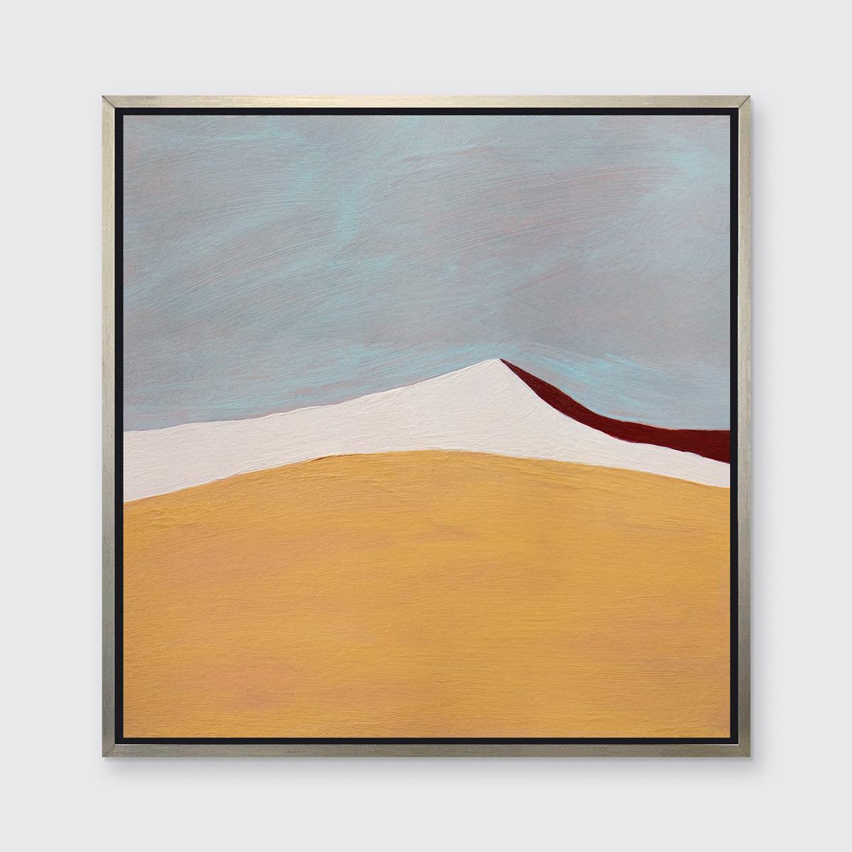 A dark yellow, white, dark red and slate blue abstract landscape print in a silver floater frame hangs on a white wall.