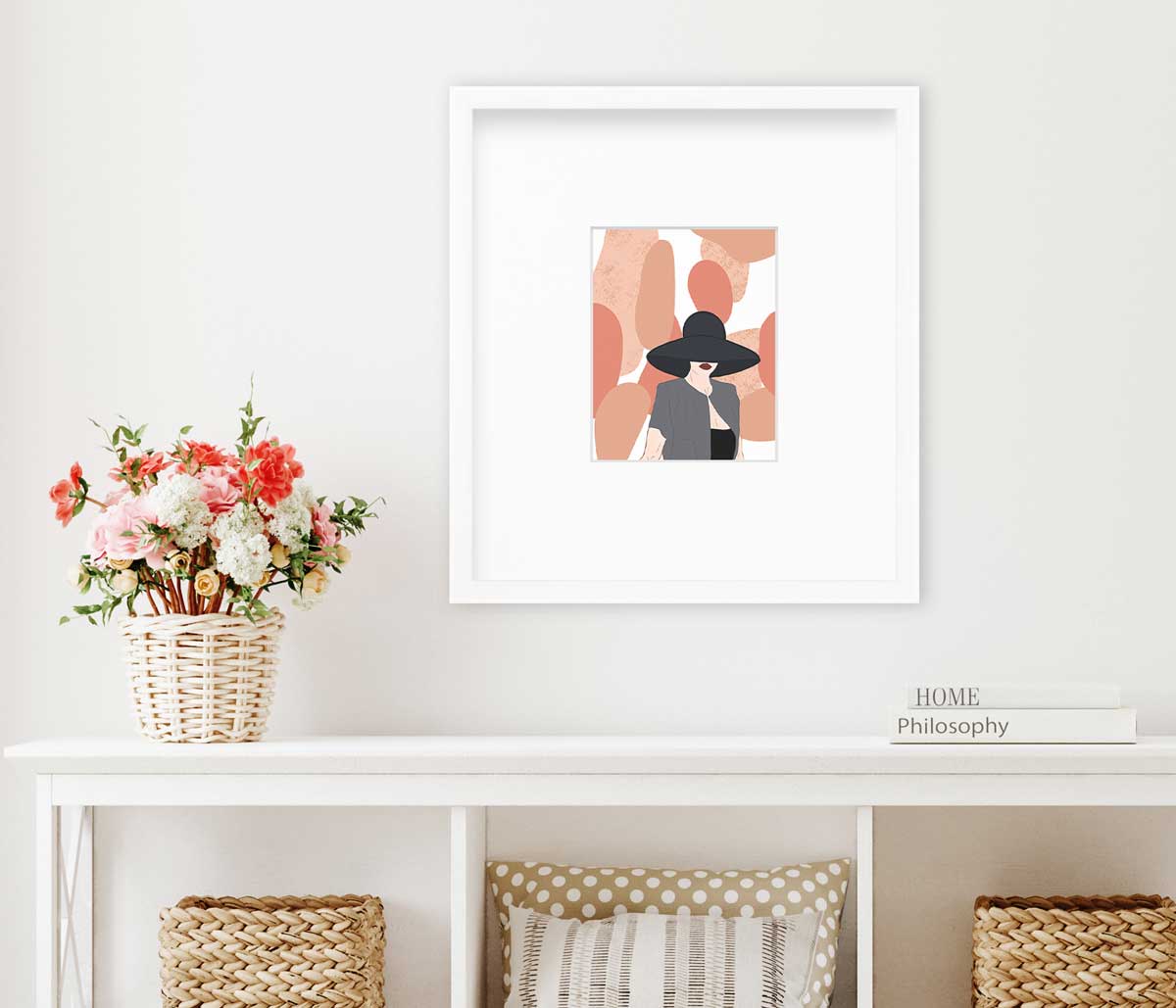 Pop art print of a woman hangs on a white wall  in a white frame with a mat above a white console table with coffee table books to the right and flowers in a wicker basket to the left. 