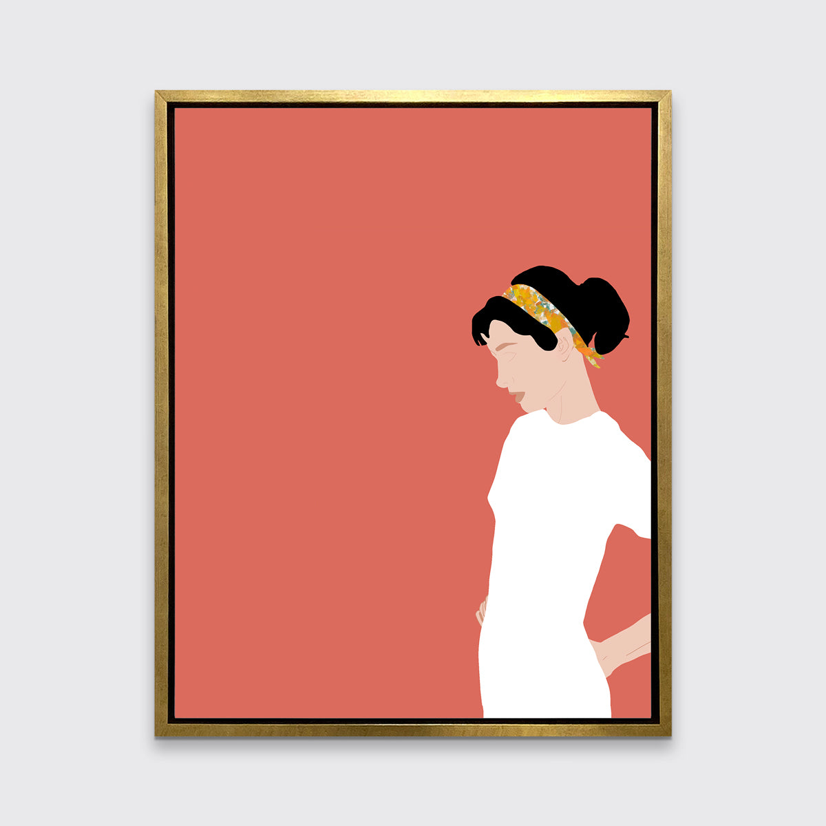 A print with a woman in a white dress and pink background, framed in a gold floater frame on a grey wall.