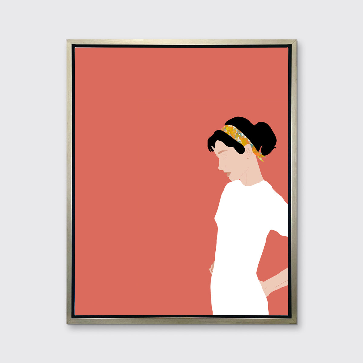 A print with a woman in a white dress and pink background, framed in a silver floater frame on a grey wall.