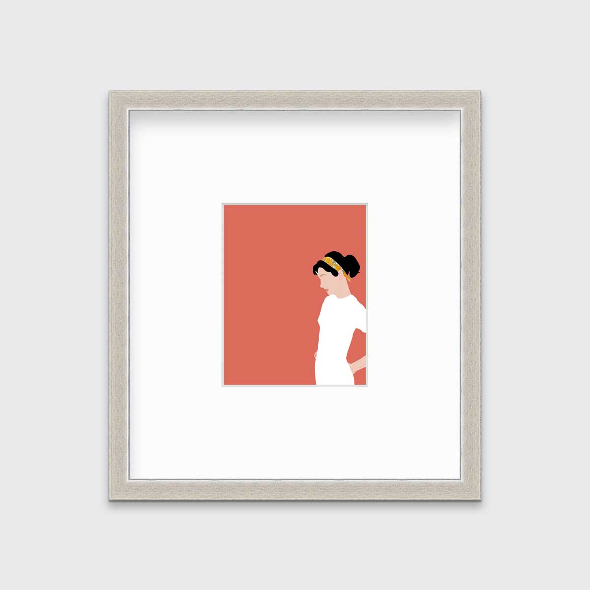 A print with a woman in a white dress and pink background, matted and framed in a silver frame on a grey wall.