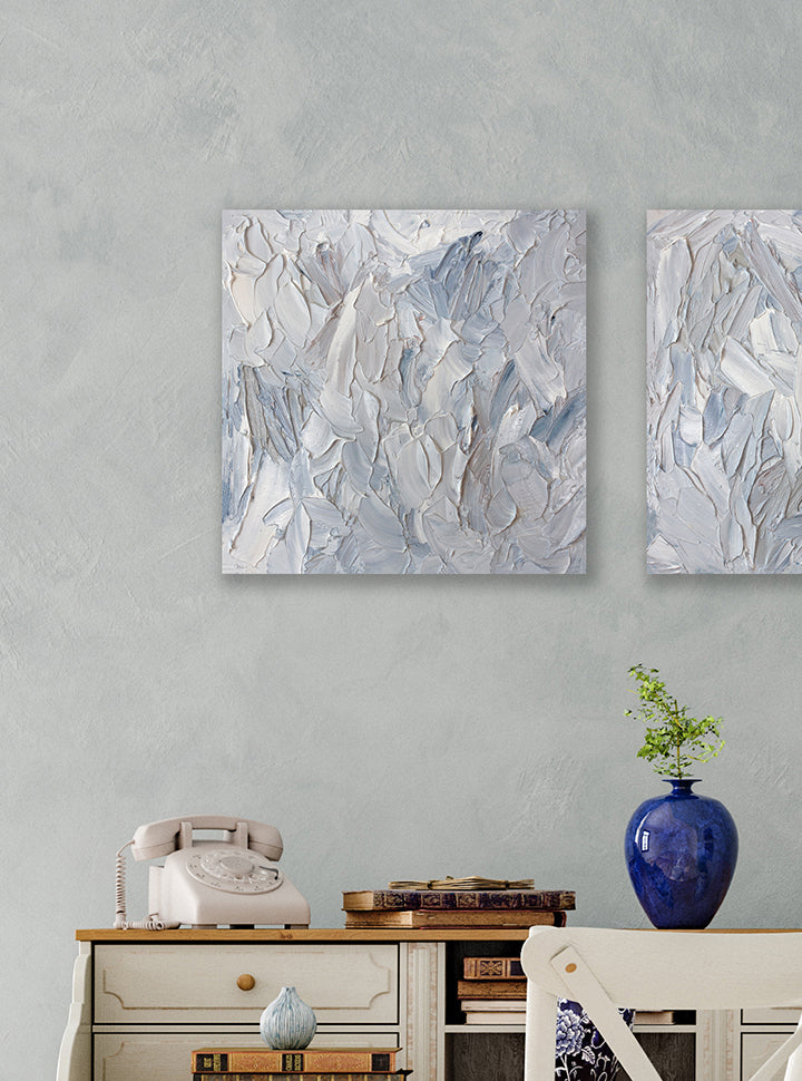 A painting is hanging on a wall. Its surface is decorated with white, blue and grey paint in a thick impasto. Hangs over a desk with rotary dial phone. Wired and ready to hang.