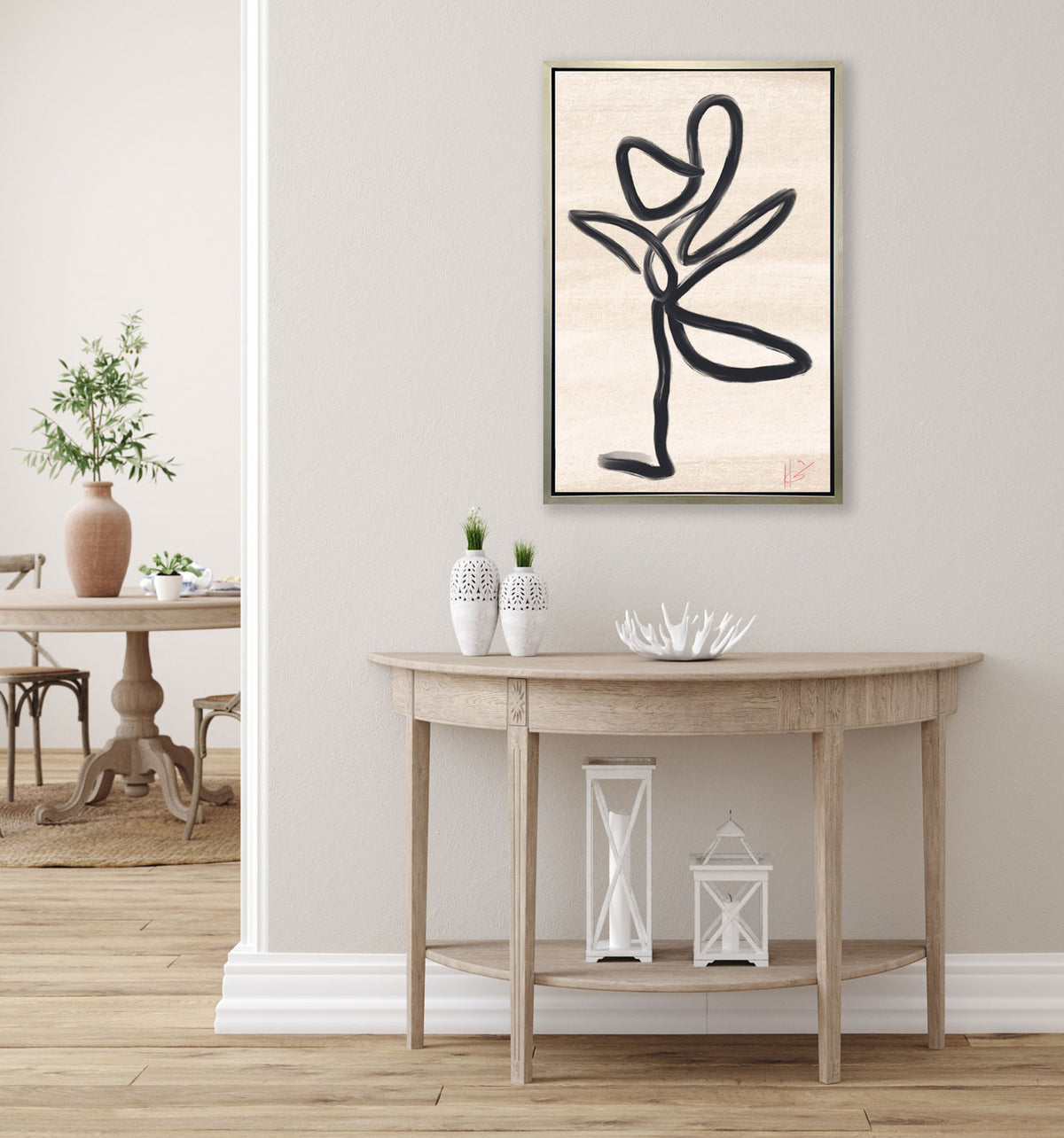 A black and beige abstract print hangs above a wooden console table and white table decor. 