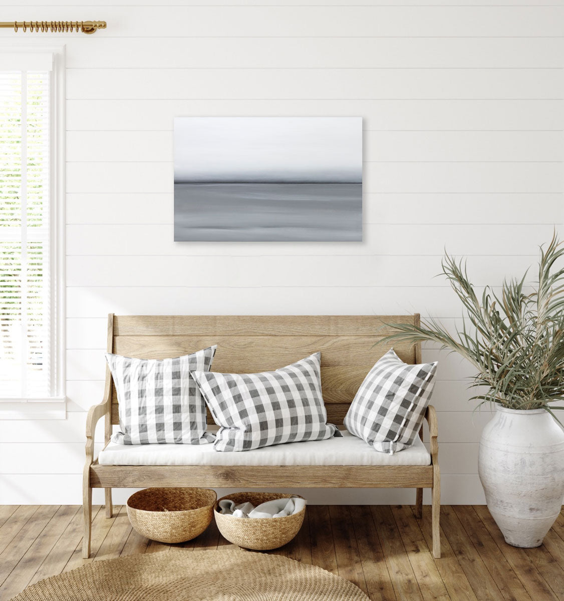A grey oil painting with a single black line in the middle of the painting that suggests a horizon line is hung above a bench. Wired and ready to hang.