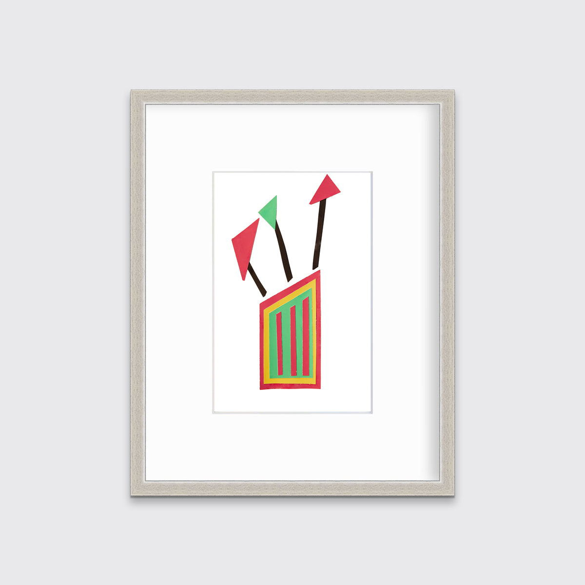 A red, yellow and black abstract collage print in a silver frame with a mat hangs on a white wall.