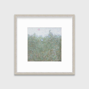 A green and blue abstract landscape print in a silver frame with a mat hangs on a white wall.