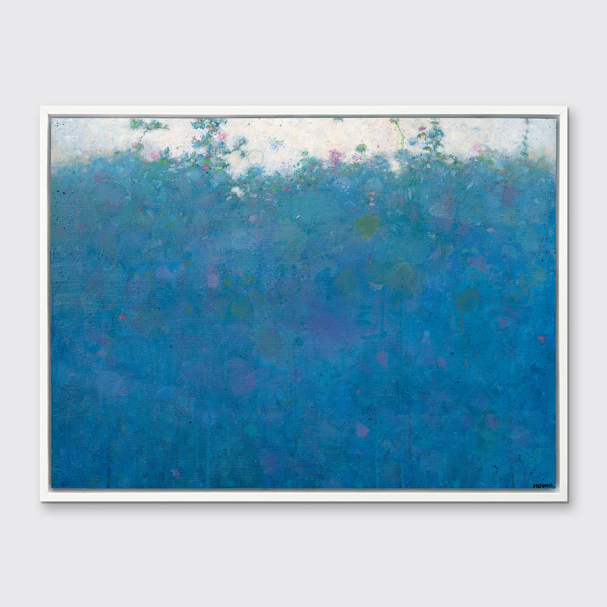 A blue, green, pink and white abstract landscape print in a white floater frame hangs on a white wall.