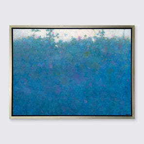 A blue, green, pink and white abstract landscape print in a silver floater frame hangs on a white wall.