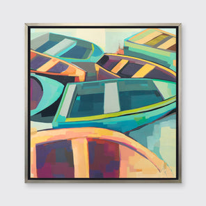 A multicolored abstract print of boats in a silver floater frame hangs on a white wall.