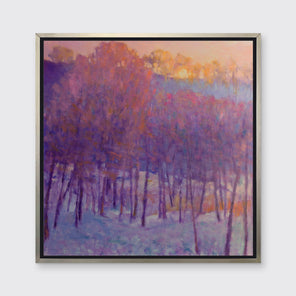 A pink and purple abstract landscape print in a silver floater frame hangs on a white wall.