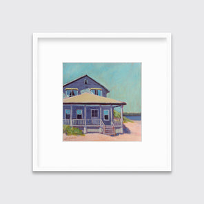 A teal, purple, beige and rose contemporary beach house print in a white frame with a mat hangs on a white wall.