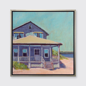 A teal, purple, beige and rose contemporary beach house print in a silver floater frame hangs on a white wall.
