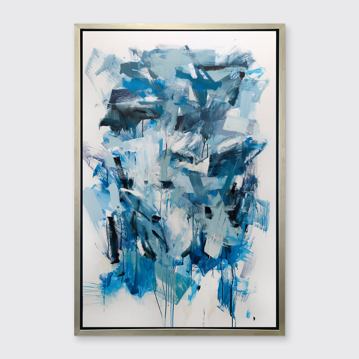 A blue, teal and white abstract print in a silver floater frame hangs on a white wall.