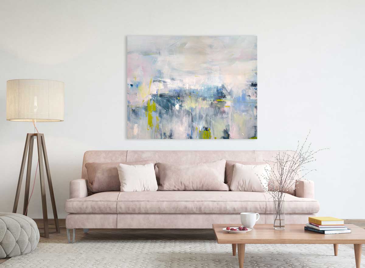 An abstract painting with energetic blue and yellow brushstrokes painted by Kelly Rossetti hangs above a pink sofa. Wired and ready to hang.