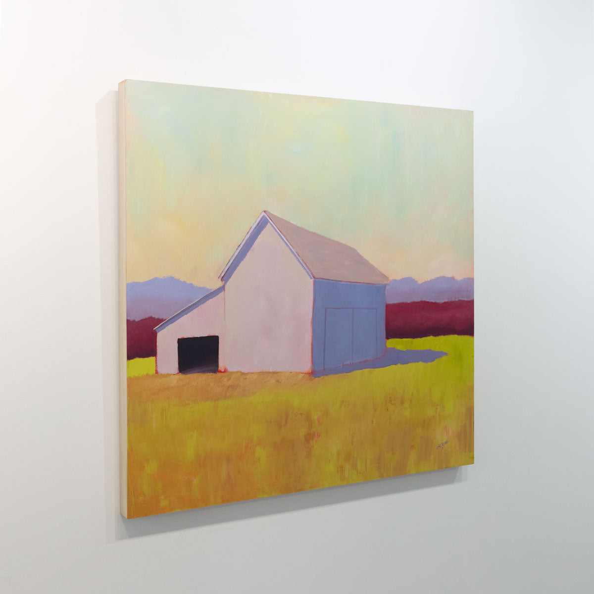 A side angle view of a painting of a barn on a gallery wall. Wired and ready to hang.