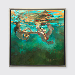A green, orange and beige abstract of two girls floating underwater holding hands in a silver floater frame hangs on a white wall.
