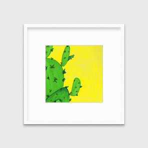 A print of a lime green cactus in front of a vibrant yellow background in a white frame with a mat hangs on a white wall.