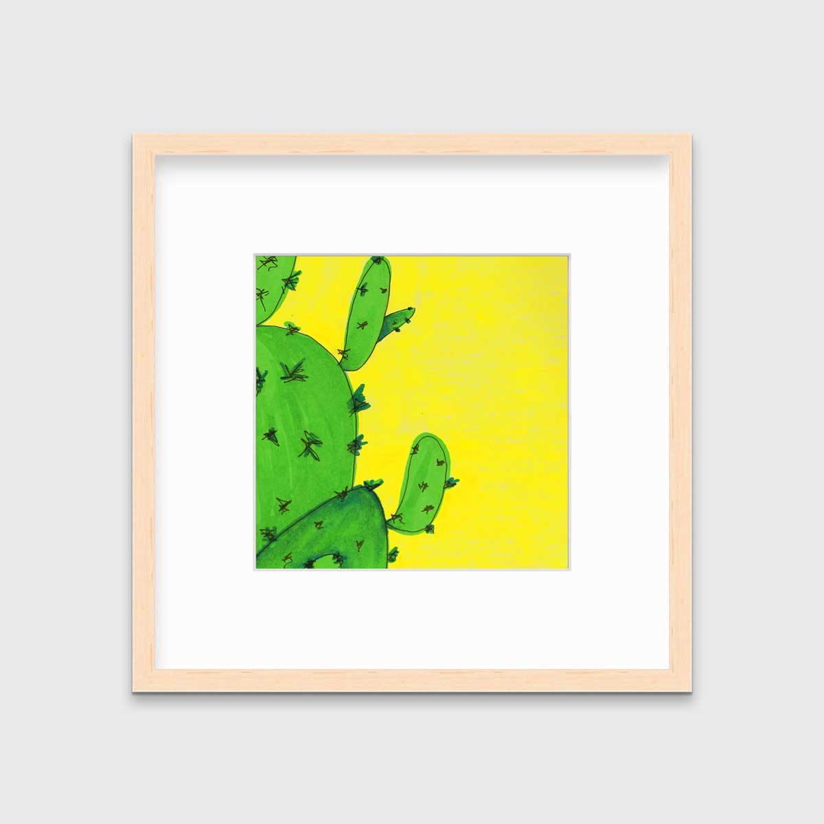 A print of a lime green cactus in front of a vibrant yellow background in a natural wood frame with a mat hangs on a white wall.