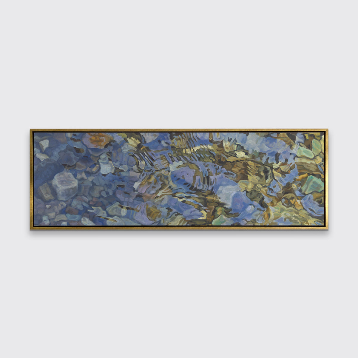 A brown, dark green, white and light blue abstract river rocks in water print in a gold floater frame hangs on a white wall.