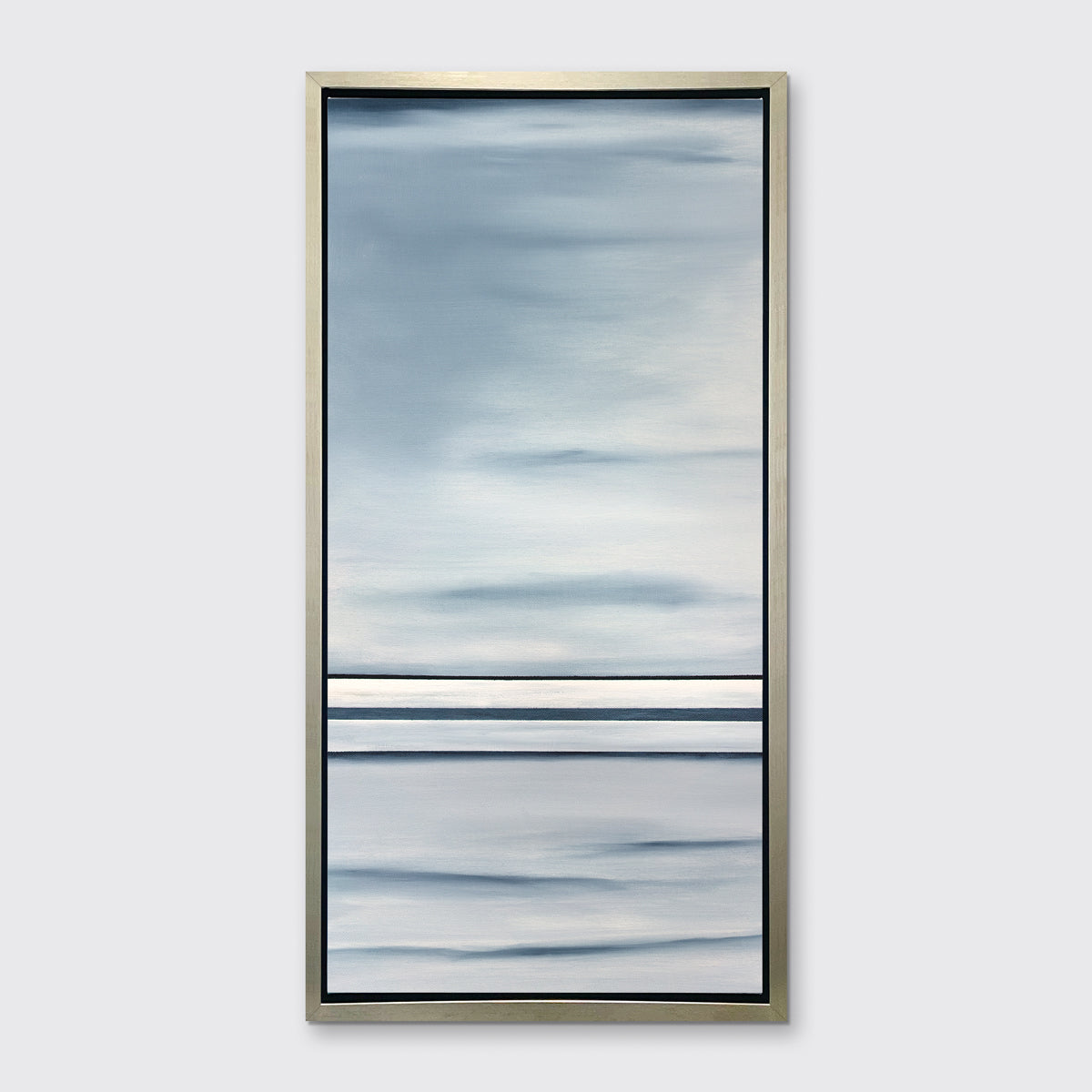 A blue and white geometric abstract print hangs in a silver floater frame on a white wall.
