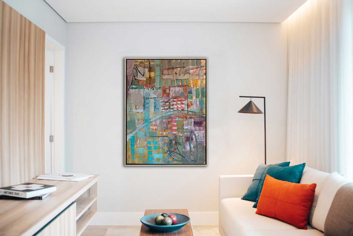 An abstract geometric print, with green, blue, yellow tones hangs on a white wall between a floor-to-ceiling window and a door, above a white couch and wooden coffee table.