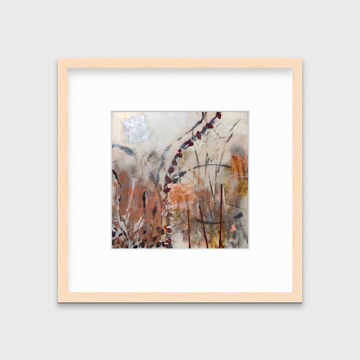 A brown, orange and gold abstract print in a natural wood frame with a mat hangs on a white wall.