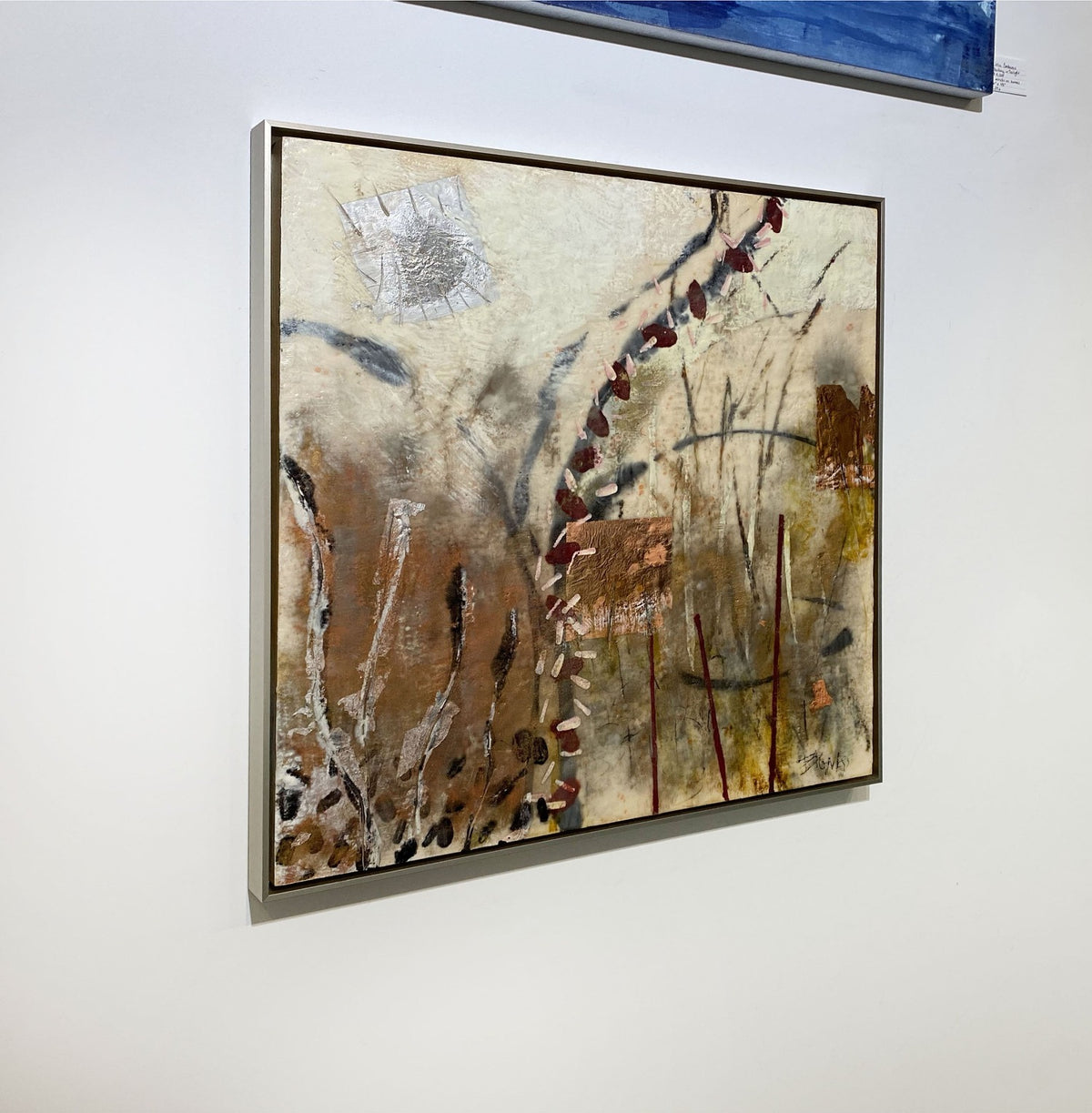 A left-hand side-angle view of a nature-inspired abstract painting by Linda Bigness hanging on a white wall. 