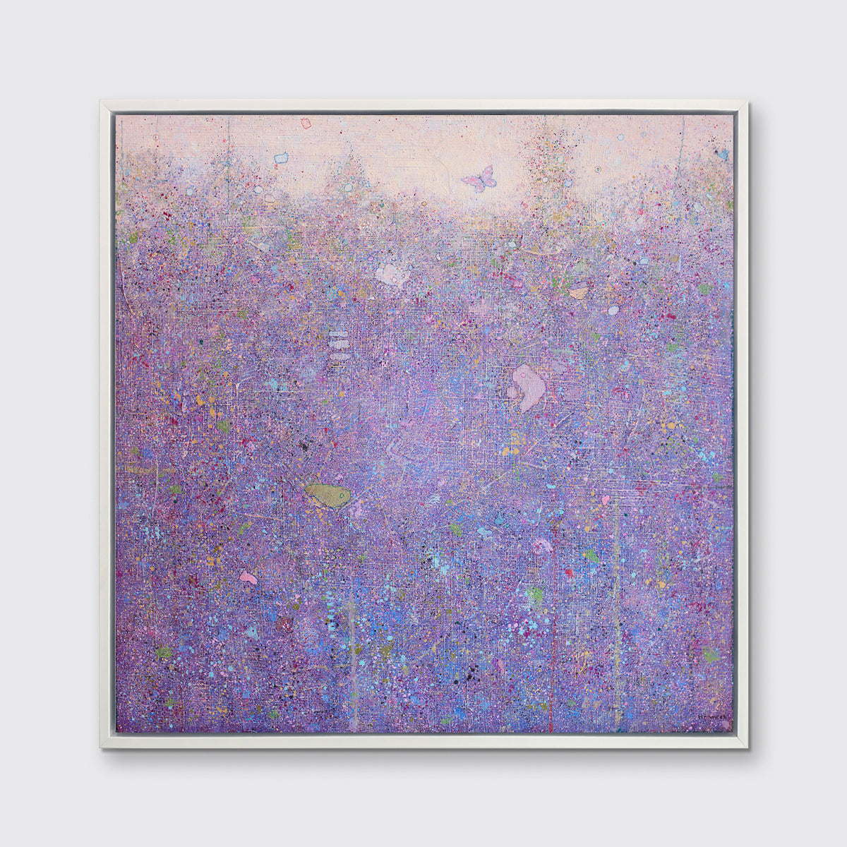 A pink abstract landscape print in a white floater frame hangs on a white wall.