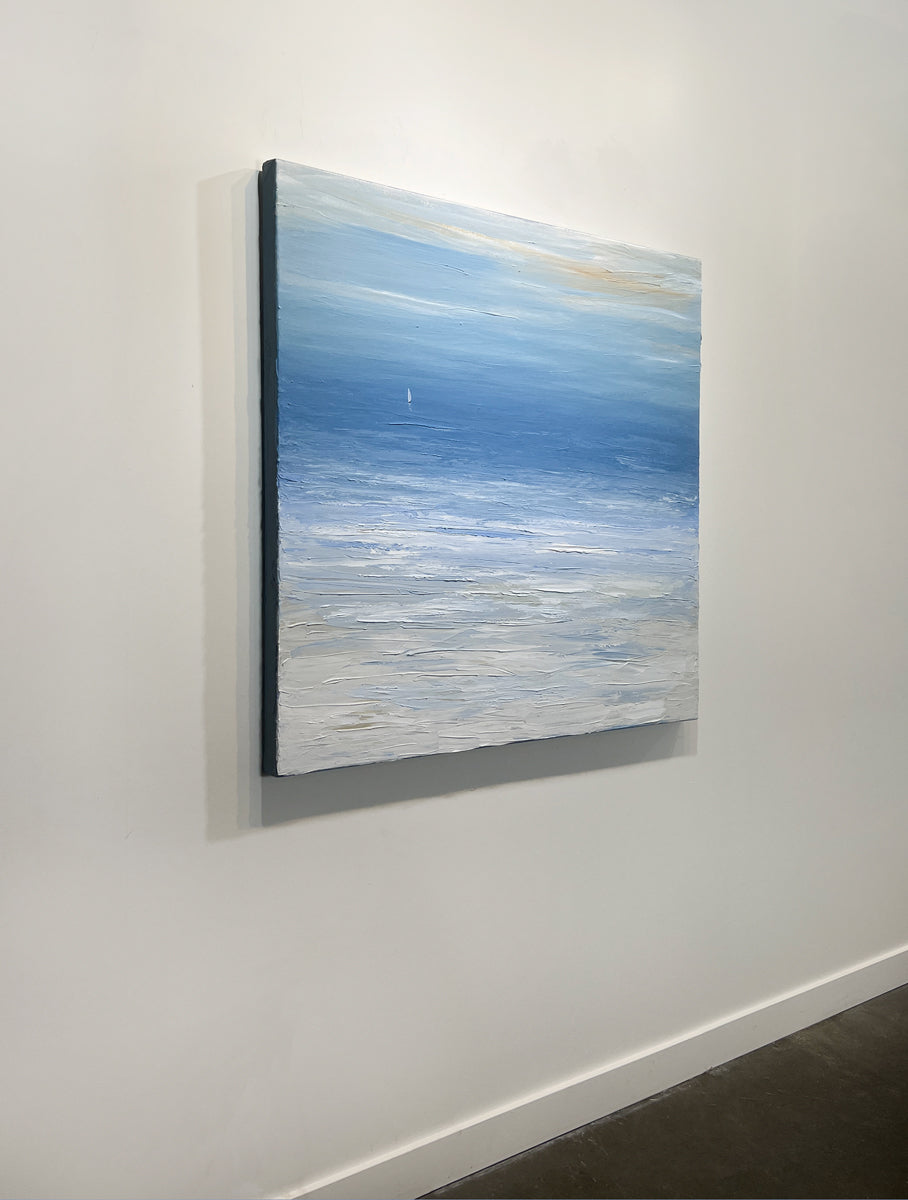 A left side-view of a blue, white and beige abstract seascape painting with a white sailboat by S. Cora Aldo hangs on a white wall.