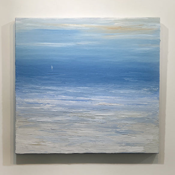 A blue, white and beige abstract seascape painting with a white sailboat by S. Cora Aldo hangs on a white wall.
