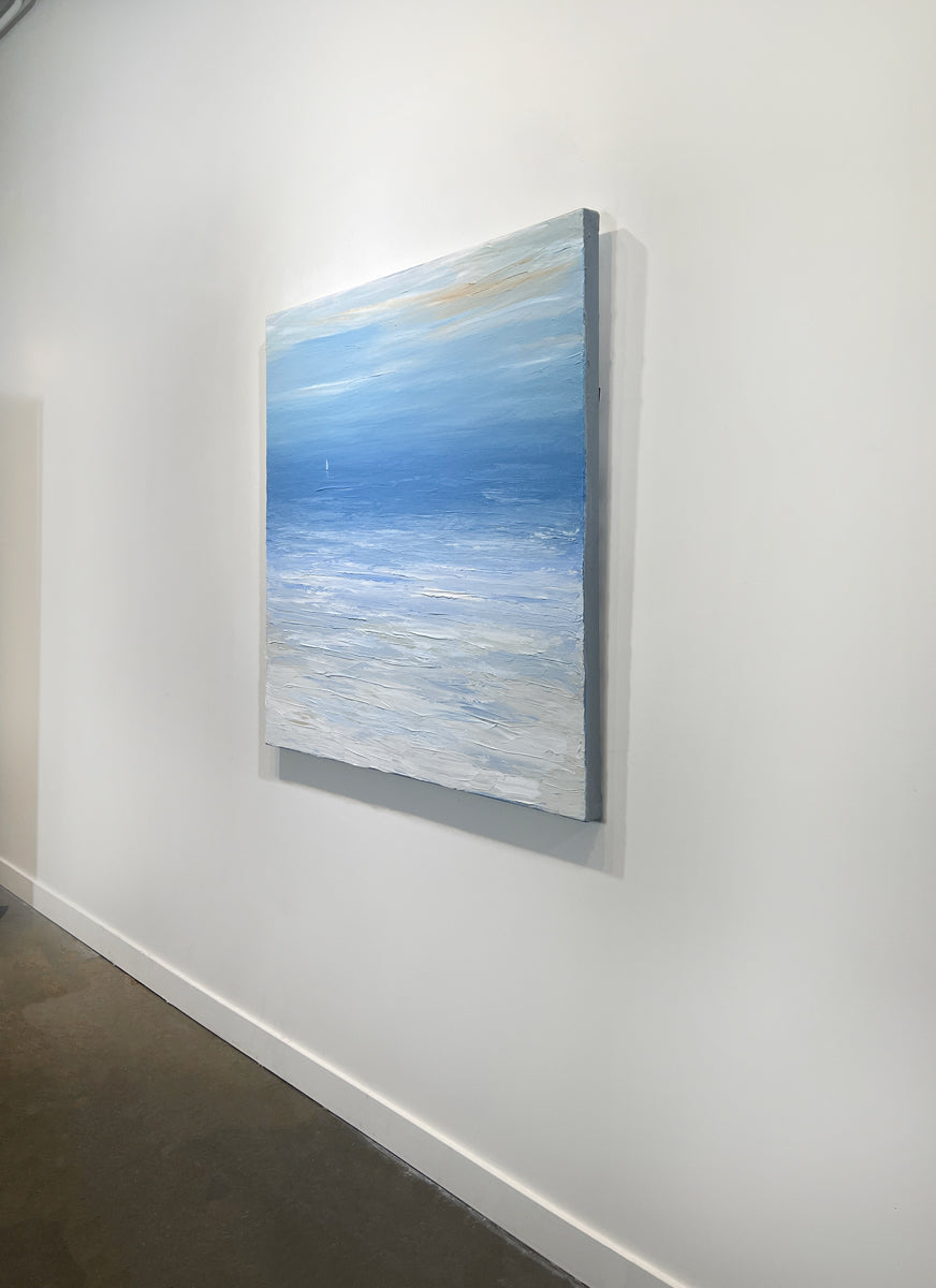 A right side-view of a blue, white and beige abstract seascape painting with a white sailboat by S. Cora Aldo hangs on a white wall.