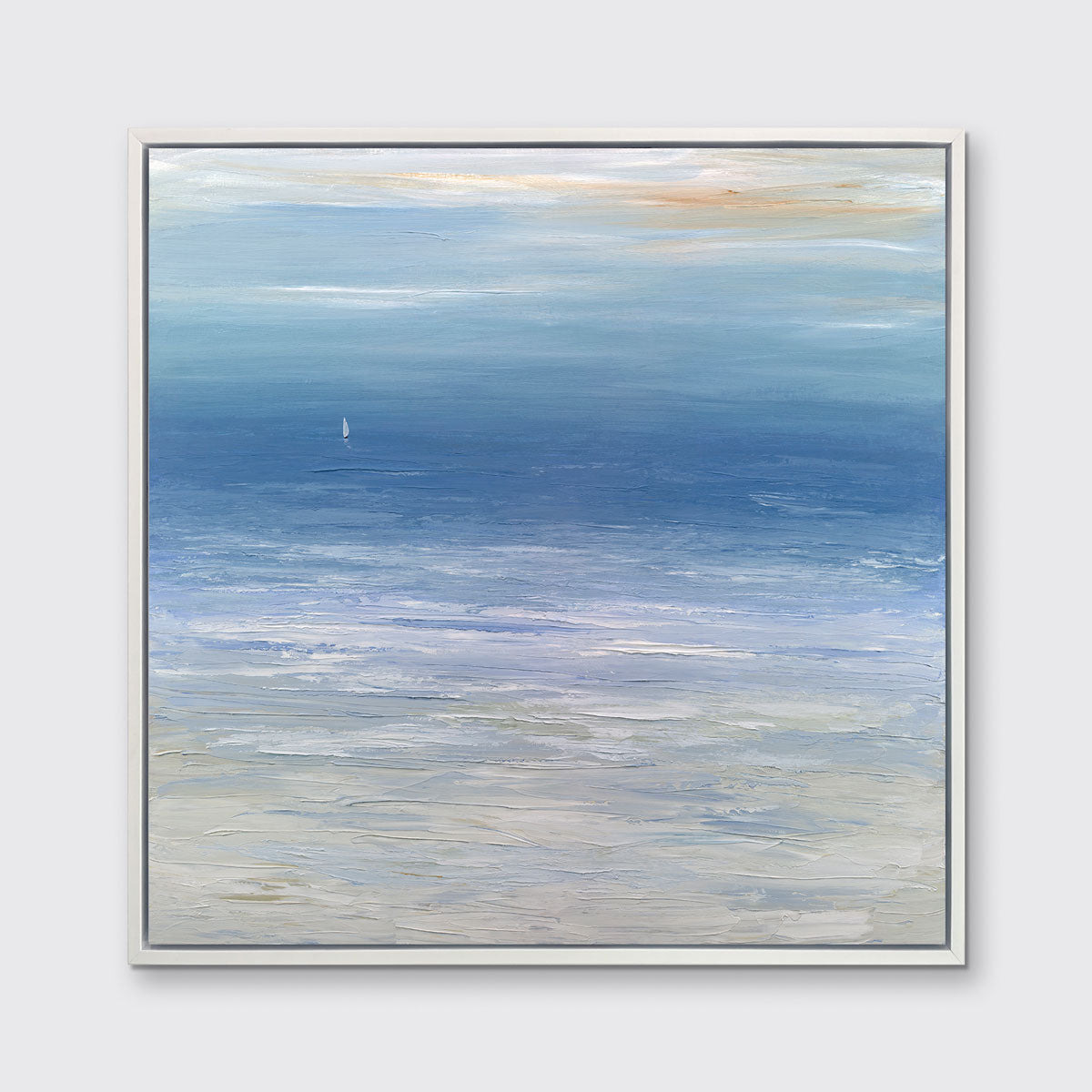 A blue, white and beige abstract seascape print in a white floater frame hangs on a white wall.