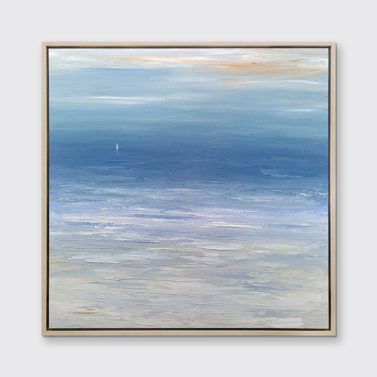 A blue, white and beige abstract seascape print in a white oak wood floater frame hangs on a white wall.