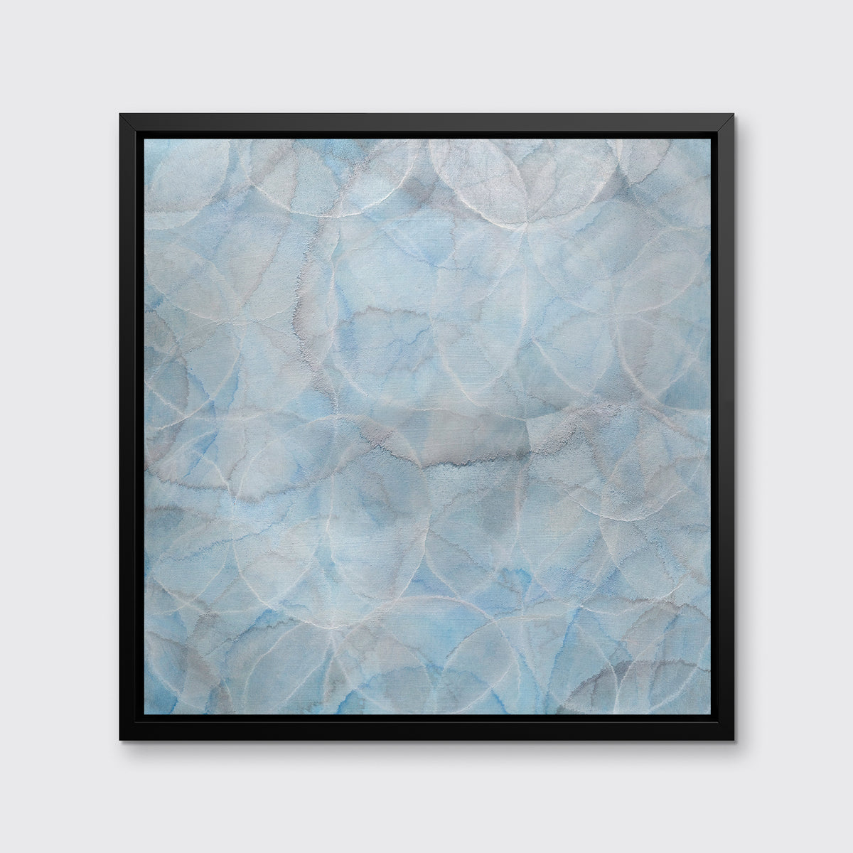 A light blue abstract overlapping circle print in a black floater frame hangs on a white wall.
