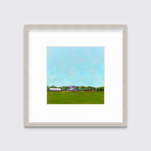 A blue, green, lavender and white landscape print in a silver frame with a mat hangs on a white wall.