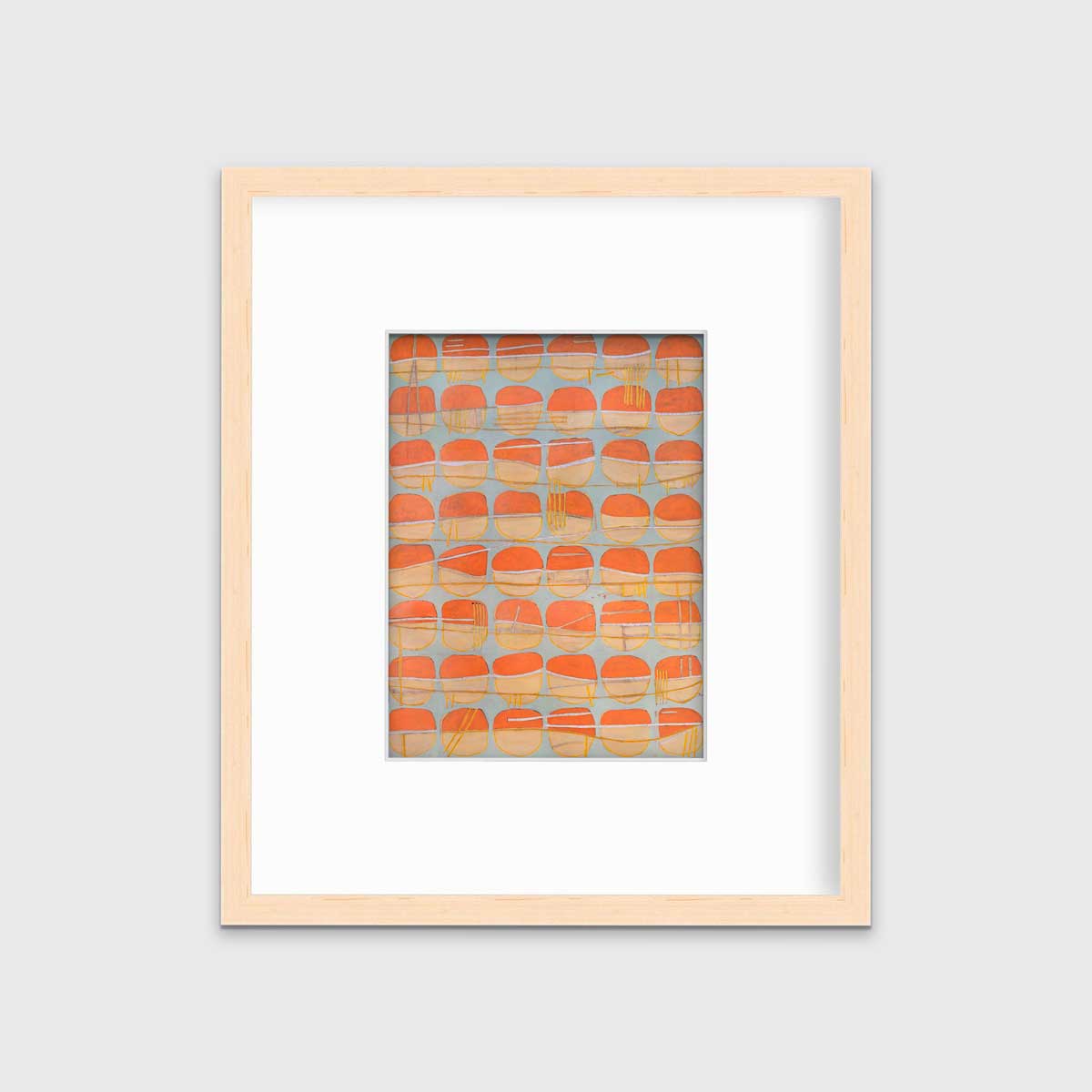 A orange, white and light blue abstract circle print in a natural wood frame with a mat hangs on a white wall.