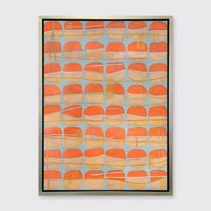 A orange, white and light blue abstract circle print in a silver floater frame hangs on a white wall.