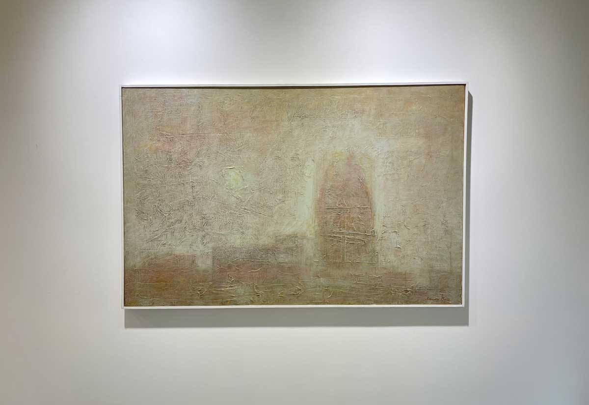 A beige abstract painting in a white floater frame hangs on a white wall.