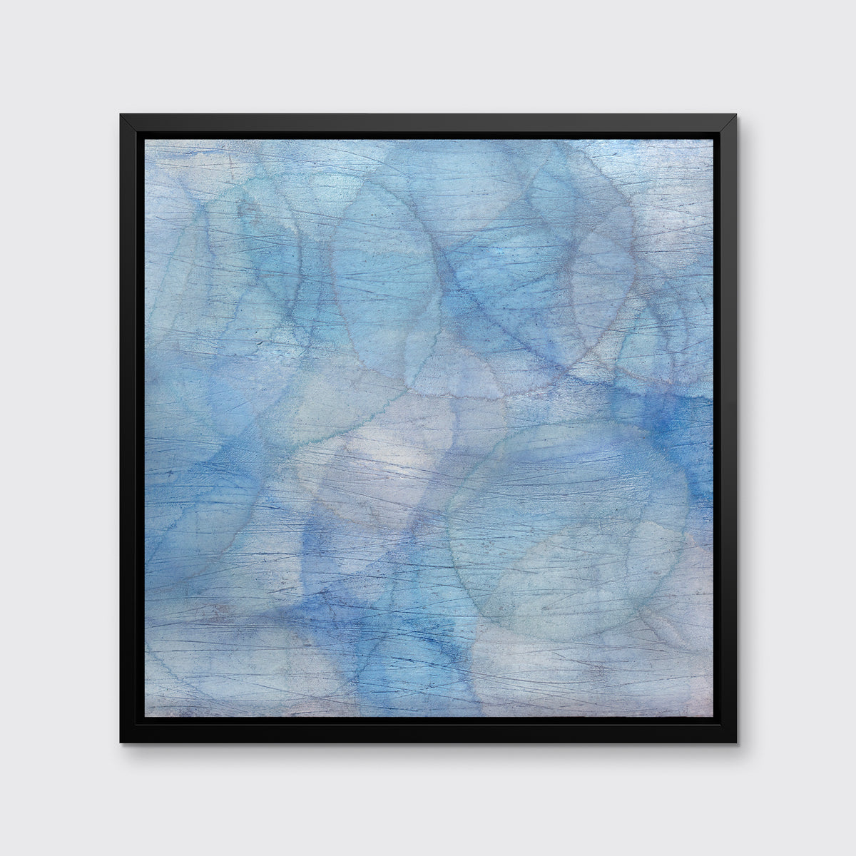 A blue and light teal abstract overlapping circle print in a black floater frame hangs on a white wall.