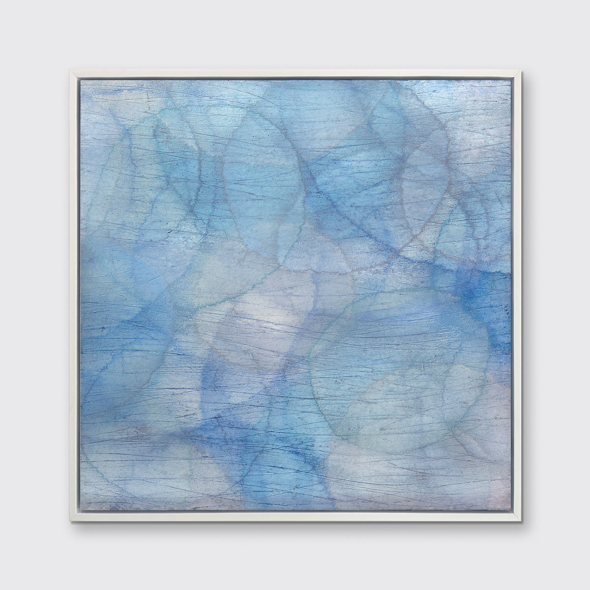 A blue and light teal abstract overlapping circle print in a white floater frame hangs on a white wall.