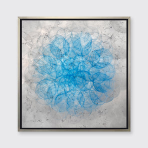 A silver, grey and blue abstract overlapping circle print in a silver floater frame hangs on a white wall.