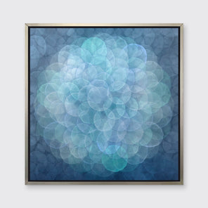 A blue, teal, light lavender and white abstract geometric print in a silver floater frame hangs on a white wall.