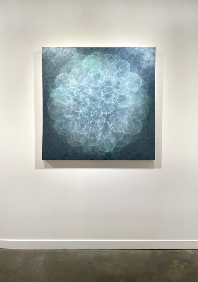 A blue, teal, light lavender and white abstract geometric painting hung on a white wall.